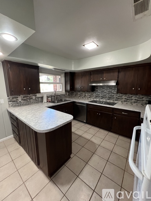 A kitchen with a white counter top and brown cabinets.