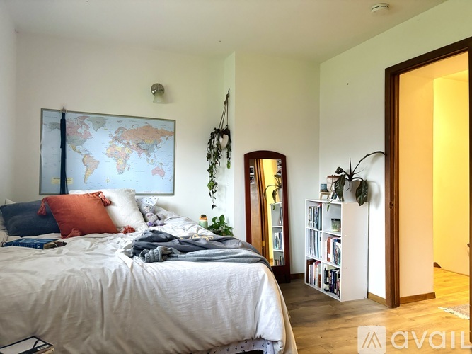A bedroom with a world map on the wall and a bed with a white comforter.