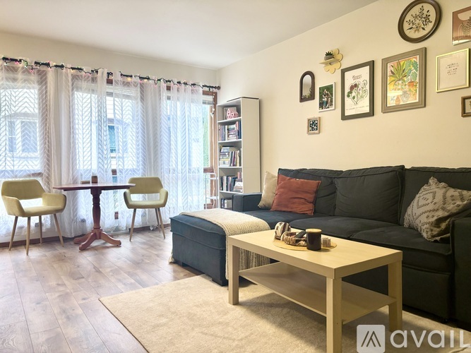A living room with a grey couch, a wooden coffee table, and a dining table with chairs.