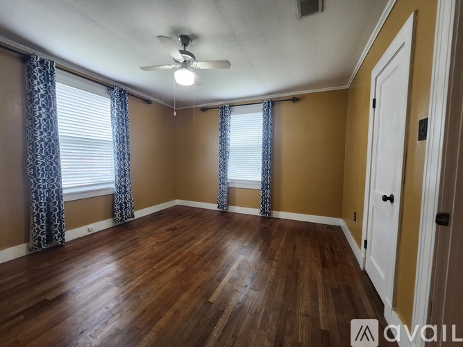 A room with a ceiling fan and wooden flooring.
