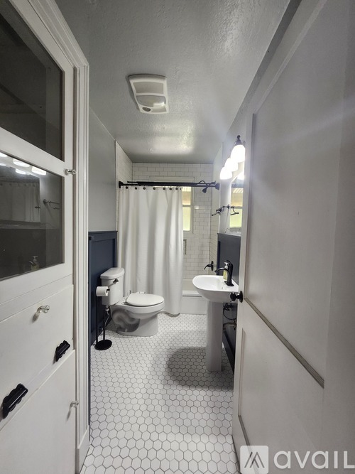 A bathroom with a toilet, sink, and shower.
