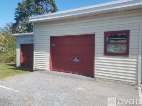 A garage with a red door is attached to a white building.