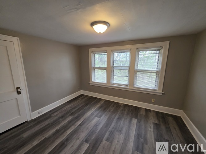 A room with a wooden floor and a window with blinds.