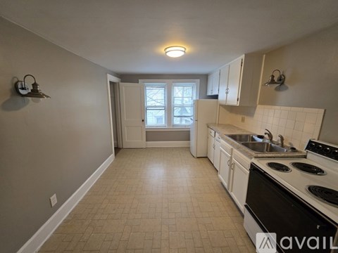 A kitchen with a black stove top oven and a window with a view of a tree.