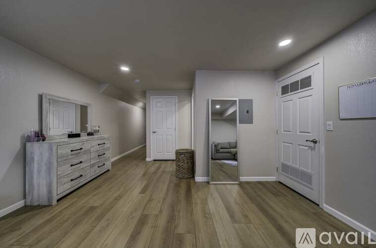 A spacious room with wooden flooring and white walls.