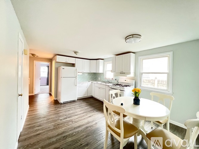 A kitchen with a table and chairs in the foreground and a refrigerator, microwave, and oven in the background.