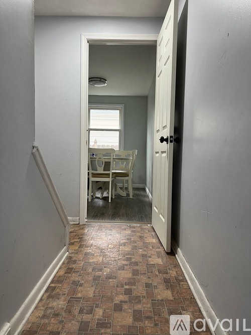 A hallway with a tiled floor and a doorway leading to a dining room.