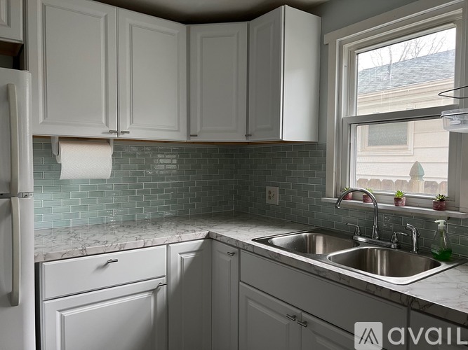A kitchen with white cabinets and a marble countertop.