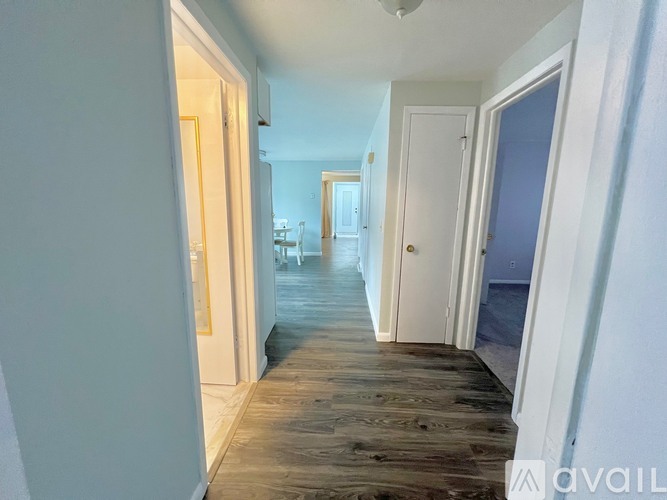 A hallway with wooden floors and white walls.