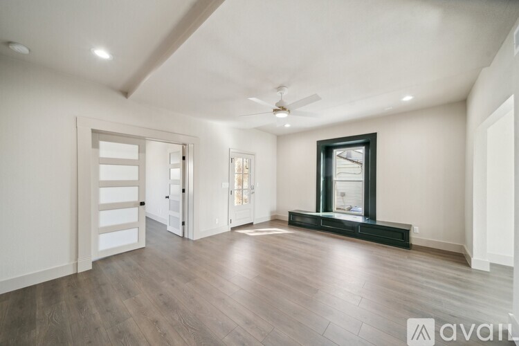 A spacious room with wooden floors and a ceiling fan.