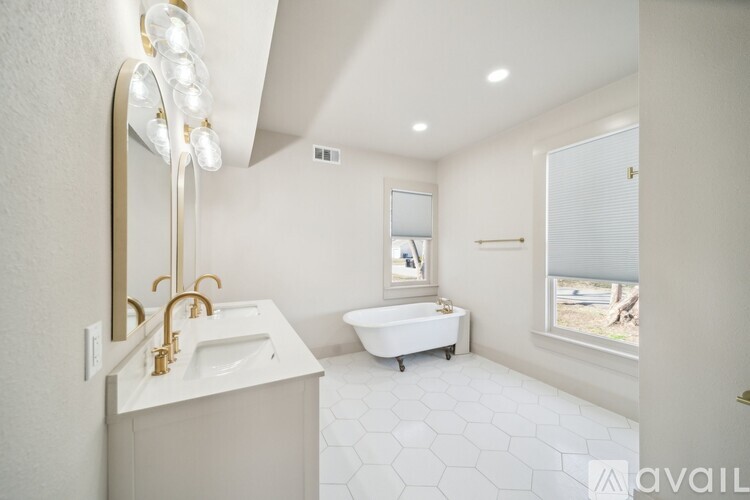 A white bathroom with a sink, mirror, and bathtub.