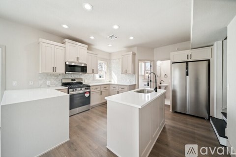 A modern kitchen with white cabinets and stainless steel appliances.