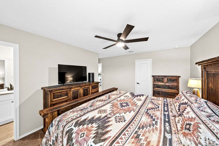 A bedroom with a bed, dresser, and ceiling fan.