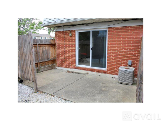 A red brick house with a patio and a wooden fence.