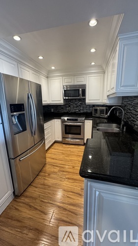 A modern kitchen with stainless steel appliances and wooden flooring.