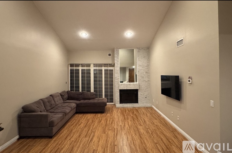 A living room with a brown couch and a flat screen TV mounted on the wall.