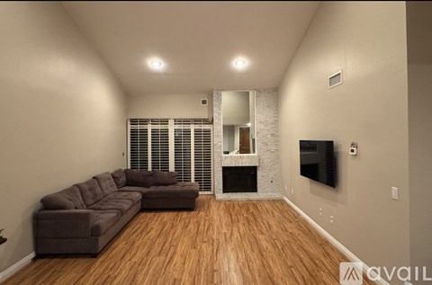 A living room with a brown couch and a flat screen TV mounted on the wall.