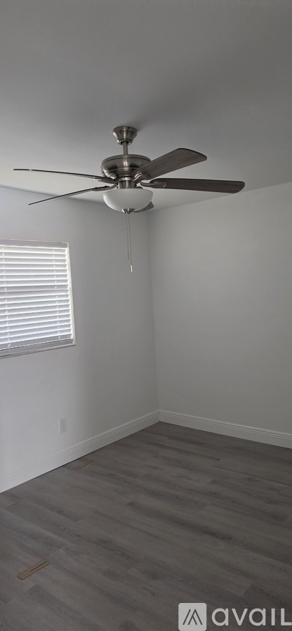 A room with a ceiling fan and a window with blinds.