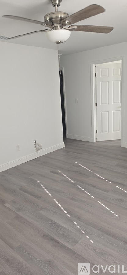 A room with a ceiling fan and wooden flooring.