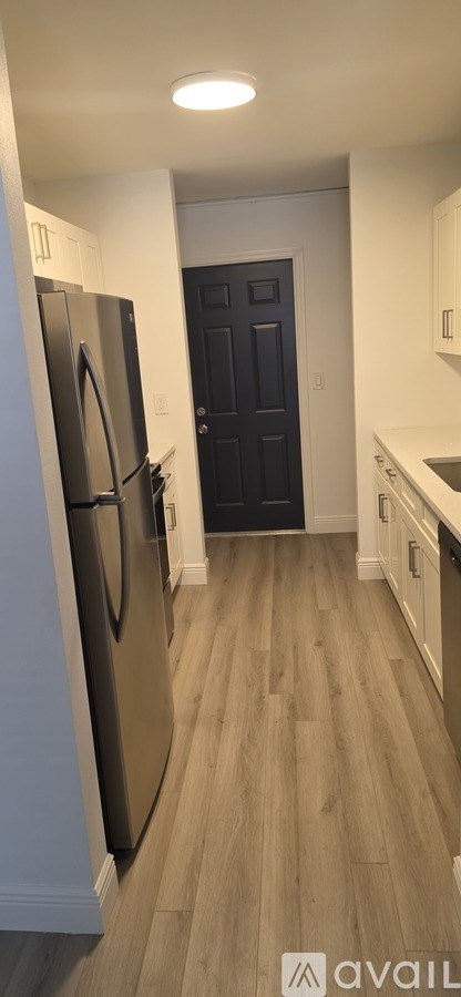 A white wall with a light switch and a wooden floor.