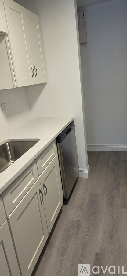 A kitchen with white cabinets and a wooden floor.