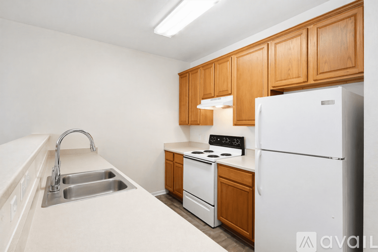 A kitchen with white appliances and wooden cabinets.