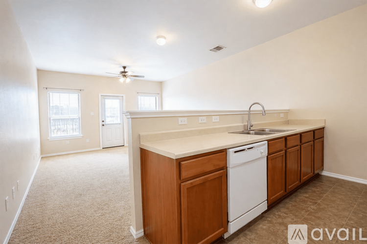 A kitchen with a white dishwasher and wooden cabinets.