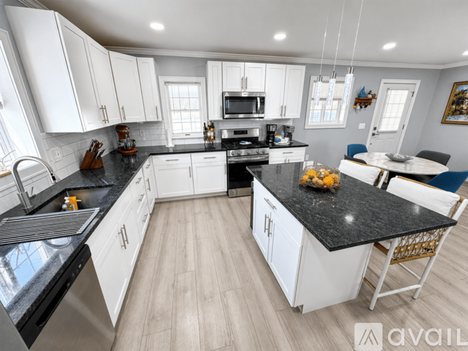 A modern kitchen with white cabinets and black countertops.
