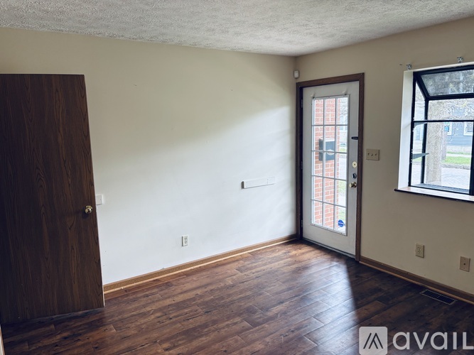 A room with a wooden floor and a door leading to a balcony.