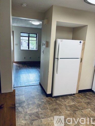 A white refrigerator is in a kitchen with a tile floor.