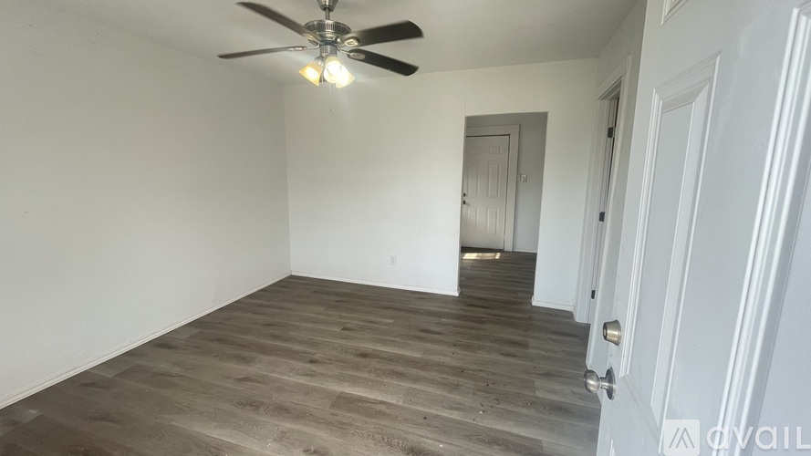 A room with a ceiling fan and wooden flooring.