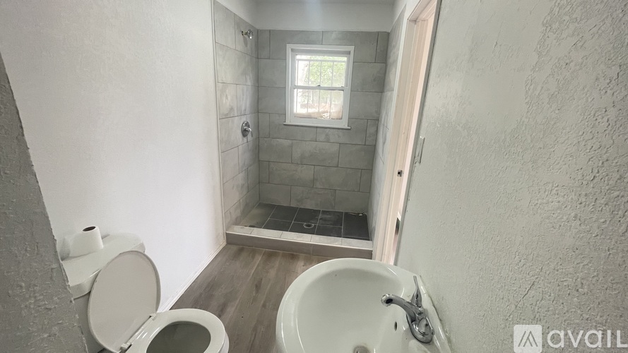 A bathroom with a toilet, sink, and a window.