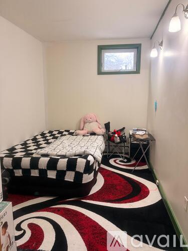 A bedroom with a black and white checkered bedspread and a red and black carpet.