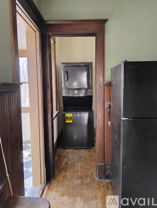 A black fridge and an old television set in a room with wooden walls.
