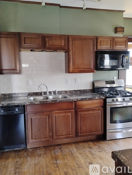 A kitchen with wooden cabinets and a black dishwasher.