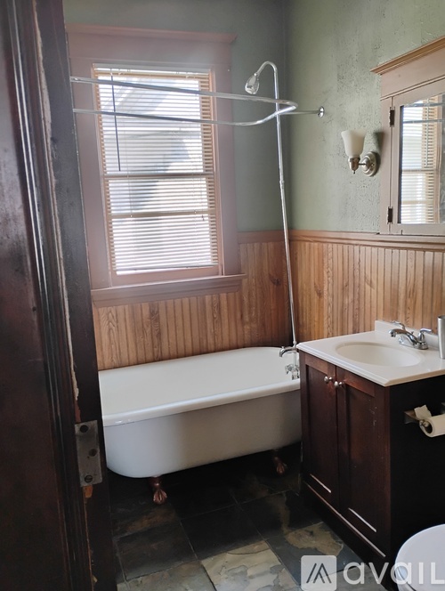A bathroom with a white bathtub, wooden walls, and a sink.