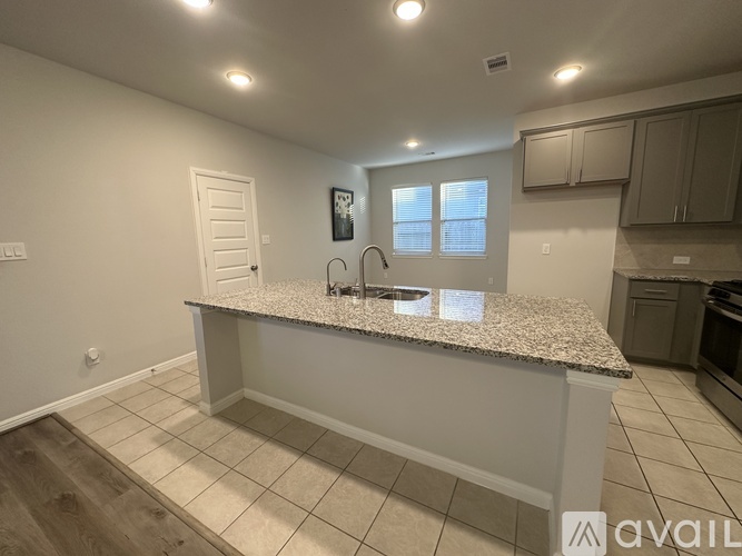 A kitchen with a granite countertop and wooden flooring.