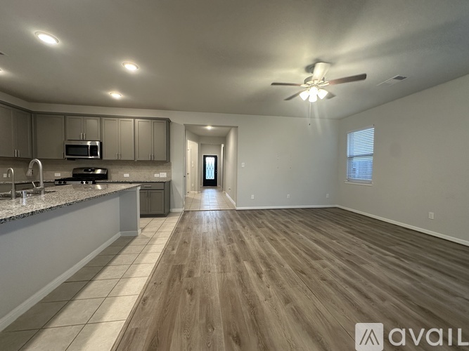 A spacious kitchen and living room with wooden flooring and a ceiling fan.