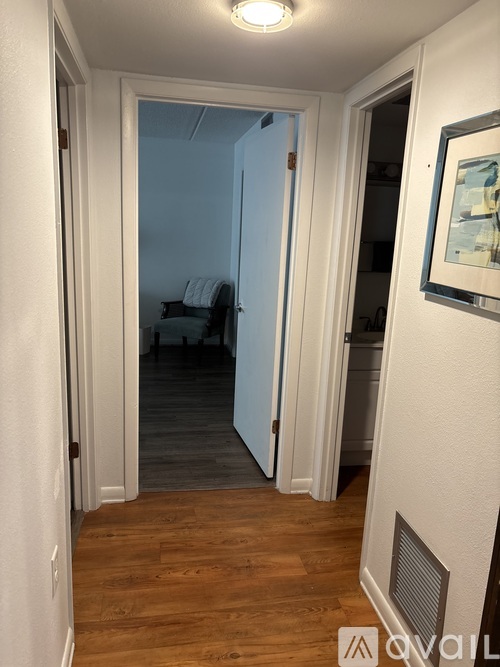 A hallway with a wooden floor and white walls.