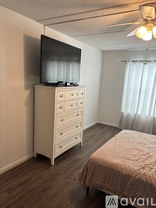 A bedroom with a bed, dresser, and television.