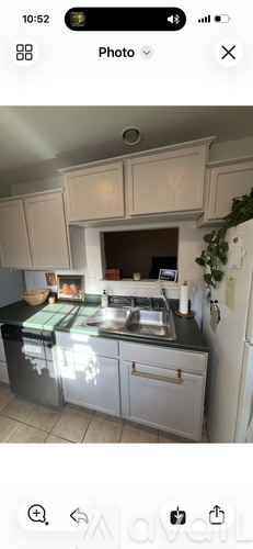A kitchen with white cabinets and a black countertop.