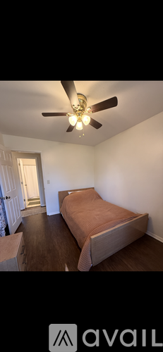 A bedroom with a bed and a ceiling fan.