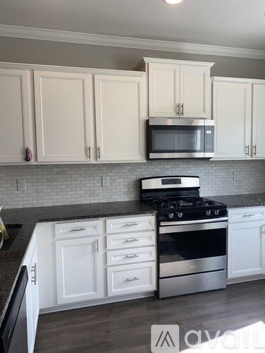 A kitchen with white cabinets and a black stove top oven.