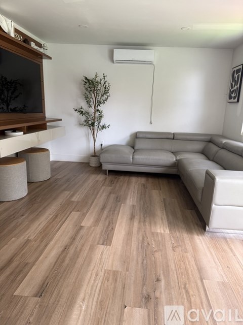 A living room with a grey couch and wooden flooring.
