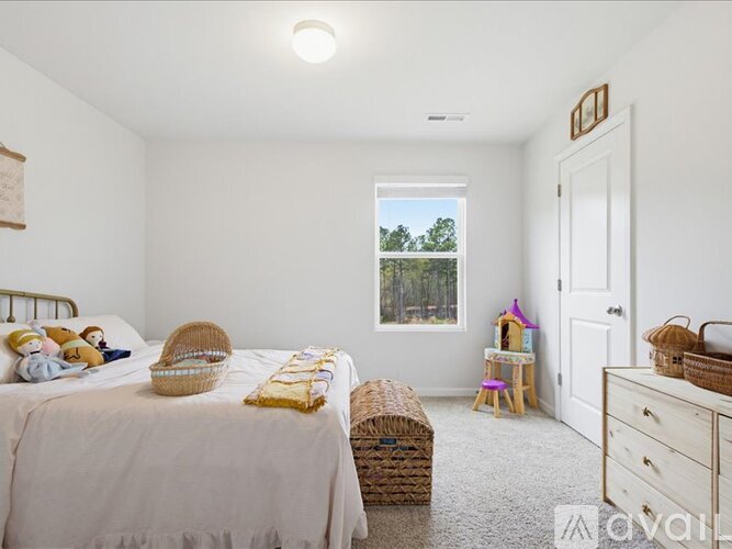 A bedroom with a large bed and a window overlooking trees.