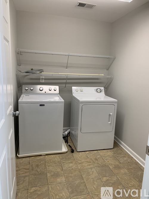 A small laundry room with two washers and a door.