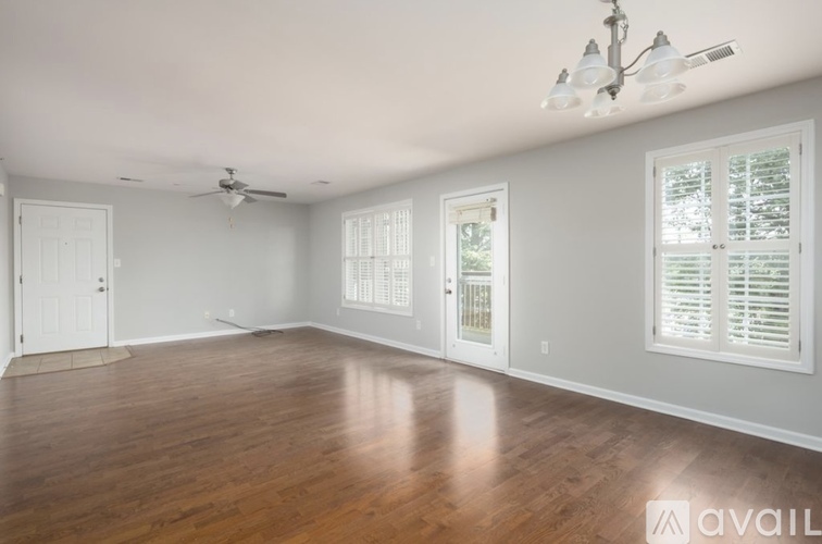 A spacious room with wooden floors and white walls.
