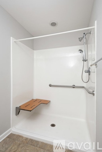 A white bathroom with a walk in shower and a bench.