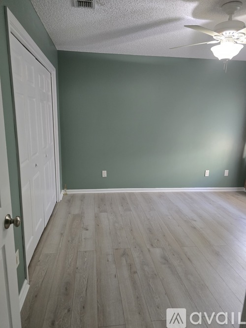A room with a white door and wooden flooring.