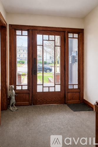 A cat is standing in front of a large wooden door.